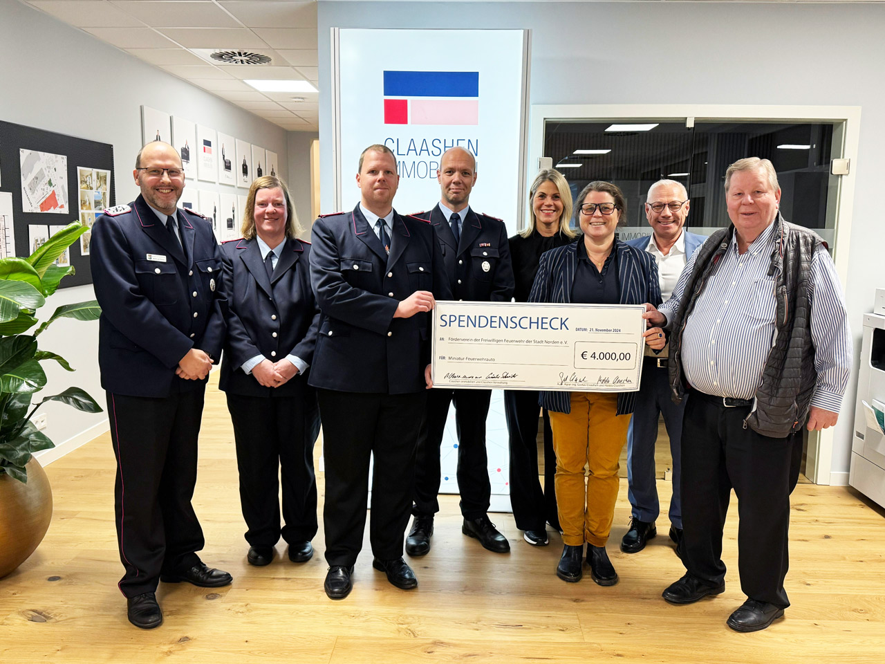 Die Geschäftsführung von Claashen Immobilien übergibt einen Spendencheck and die Freiwillige Feuerwehr Norden