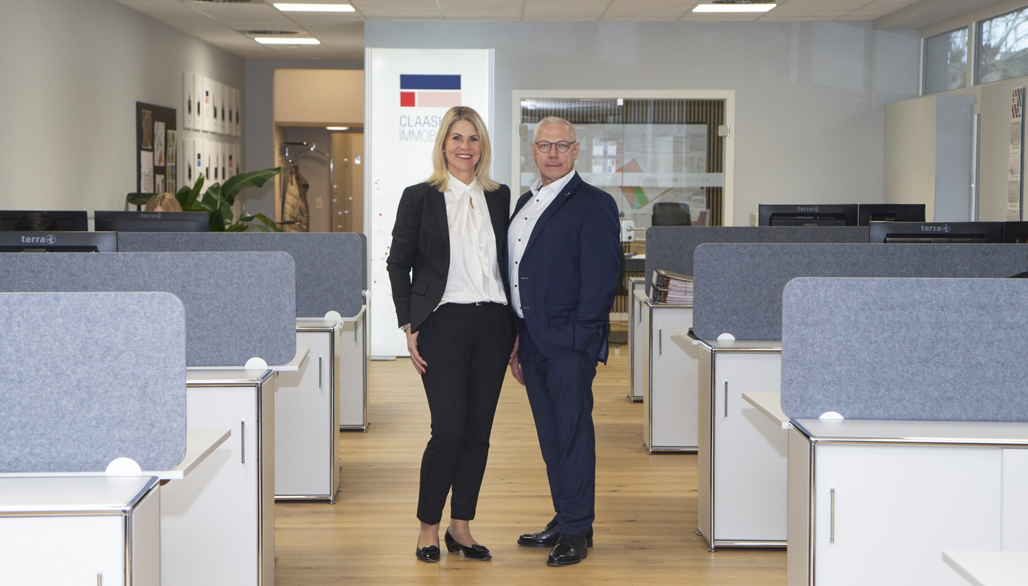 Anja Claashen-Schneider und Günter Schneider stehen in den Geschäftsräumen des Familienunternehmens Claashen Immobilien